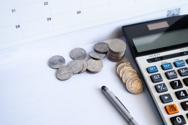 A calculator sits next to coins and a calendar.