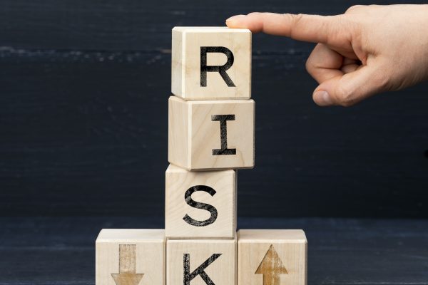 A hand pointing to a stack of wooden blocks with the word risk written on them.